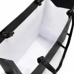 Visão interna de sacolas de papel personalizadas pretas mostrando fundo reforçado para sacola de presente.